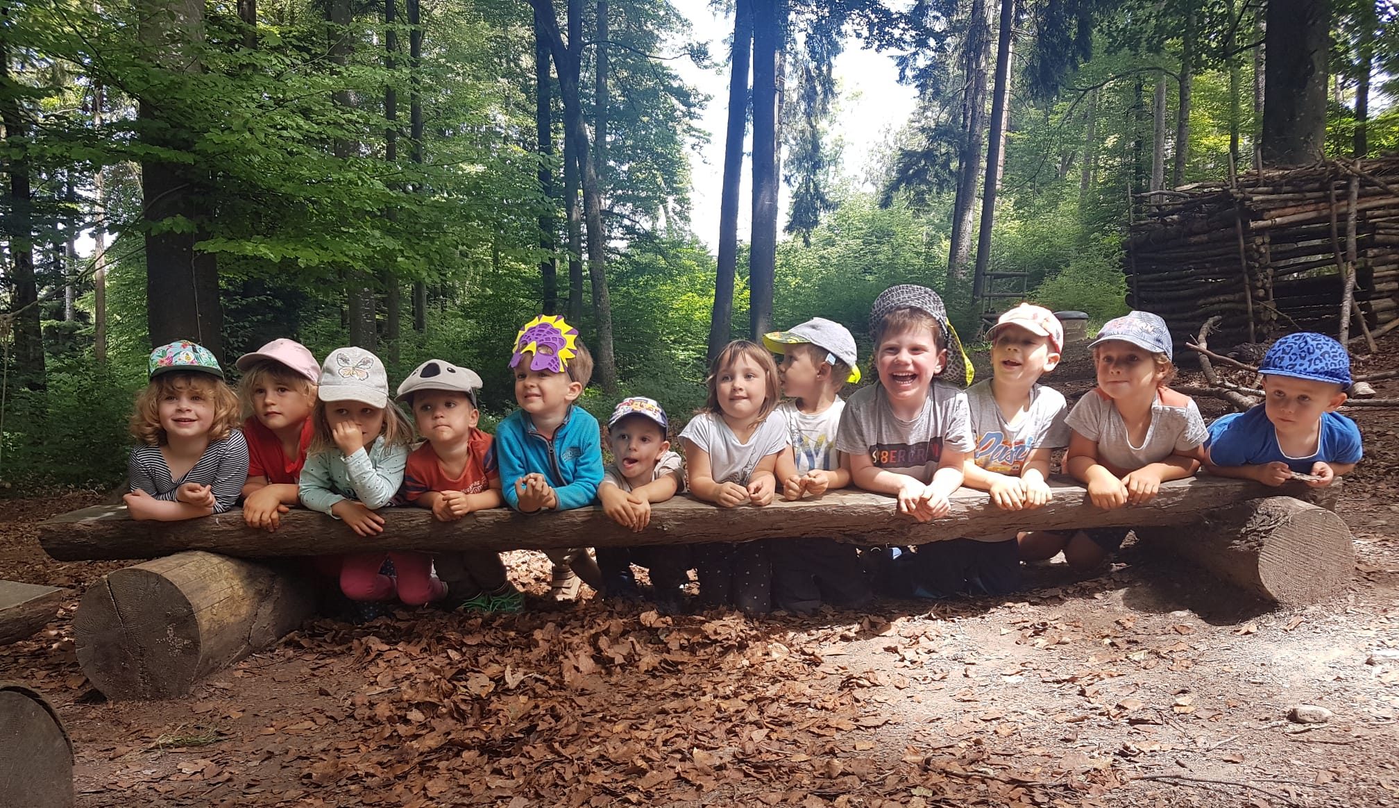 Kinder von der Waldspielgruppe auf einem Baumstamm